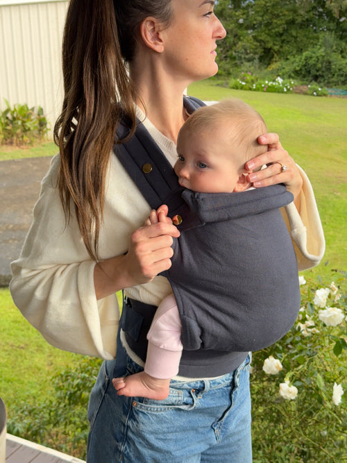 Coast | Mum carrying baby in August baby carrier outside with flowers